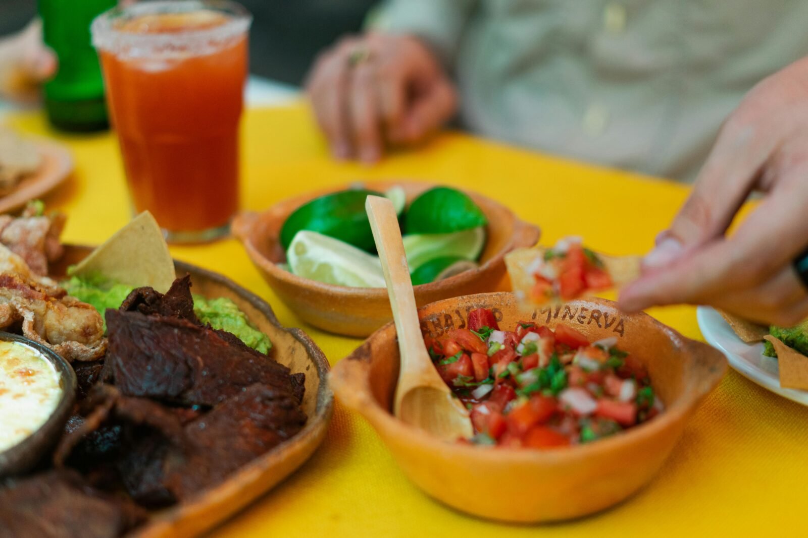 Close-up of a delicious Mexican feast featuring salsa, beef, and lime on a vibrant table setting.