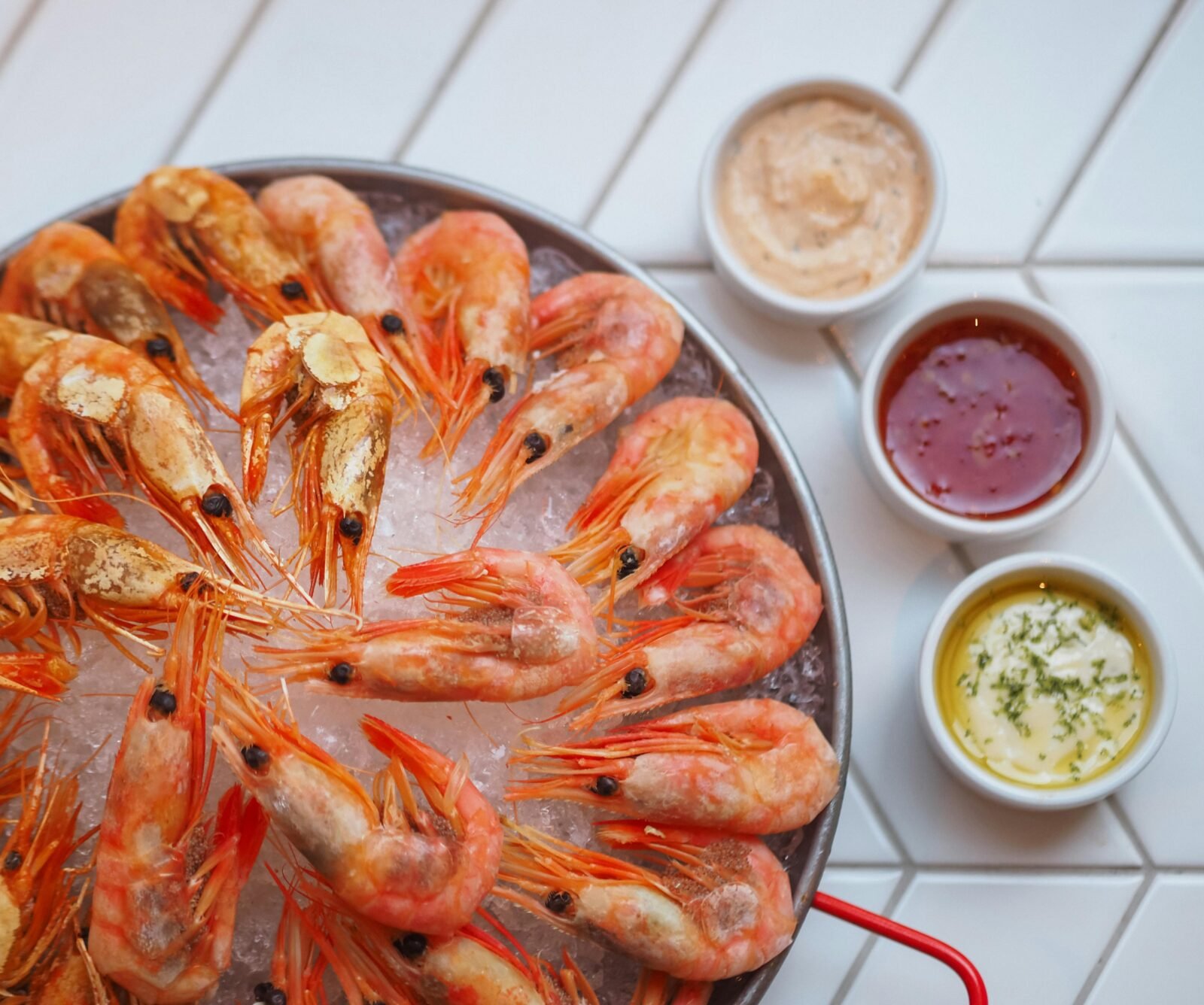 Fresh shrimps on ice with flavorful dipping sauces in a vibrant food presentation.